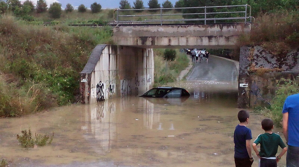 Un coche prácticamente cubierto por el agua bajo un puente en el término municipal de Tafalla después de una la gran tormenta del 8 de junio