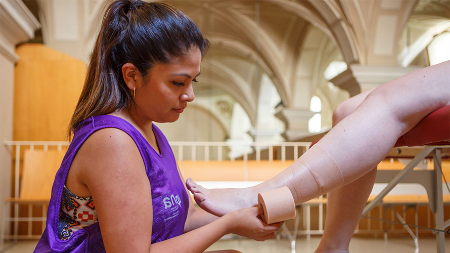 Una estudiante de Fisioterapia atiende a un peregrino aplicándole un vendaje