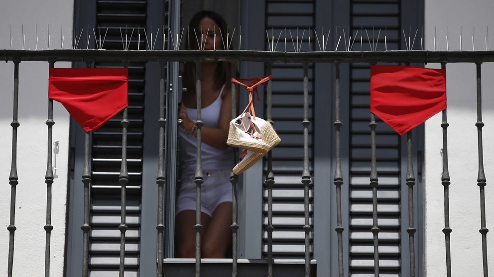 Una chica cierra la puerta de un balcón en una calle de Pamplona tras el segundo encierro de los Sanfermines 2017. EFE/Javier Lizón
