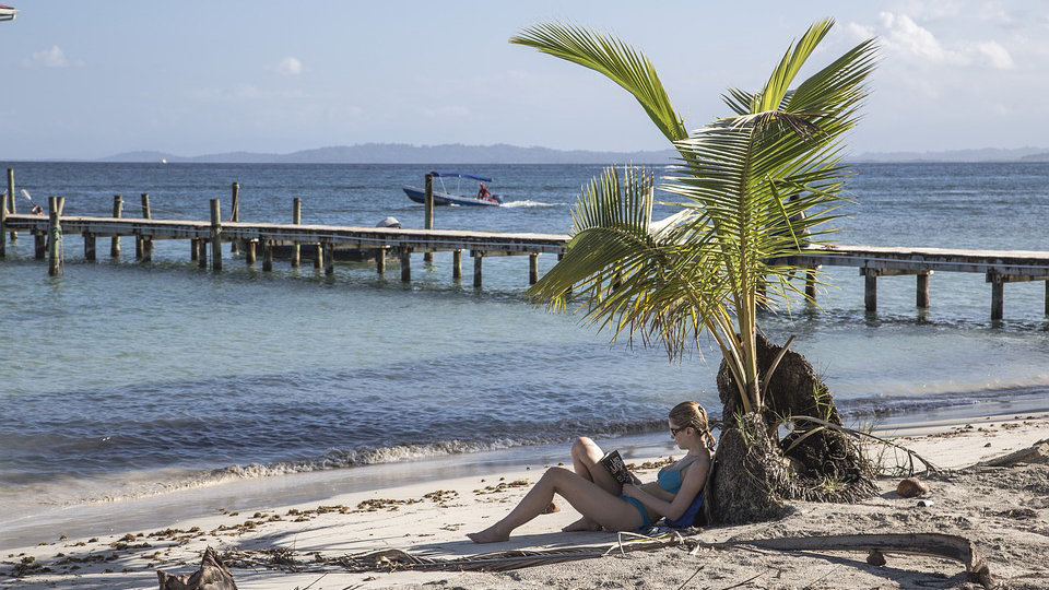 Una mujer leyendo un libro en una playa durante las vacaciones.