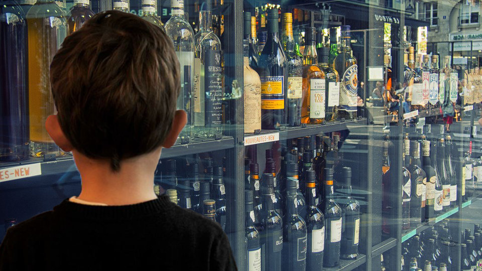 Un niño observa una vitrina con botellas de alcohol en una tienda NAVARRACOM