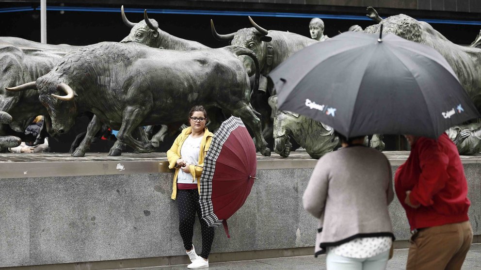 Un grupo de turistas se fotografían junto al Monumento al Encierro en Pamplona en una jornada donde las temperaturas, que no sobrepasan los 15 grados, y la lluvia hacen que el día sea mas típico del otoño que de agosto. EFE/Jesús Diges