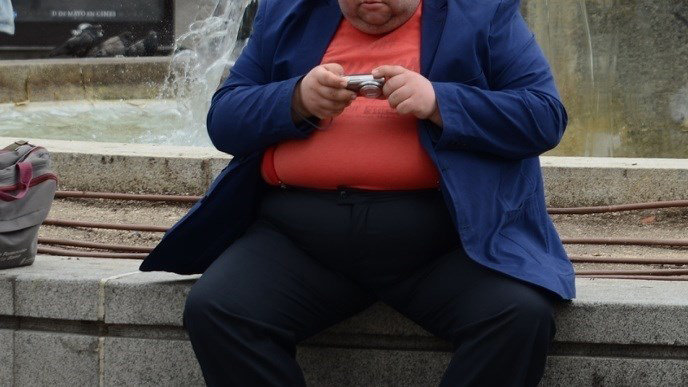 Un hombre con sobrepeso examina unas fotos de su cámara
