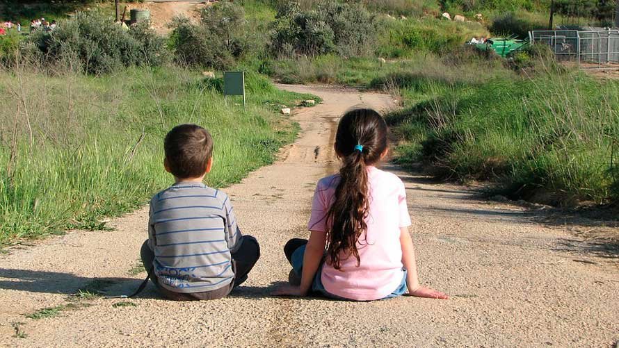 Dos niños sentados en un camino. ARCHIVO