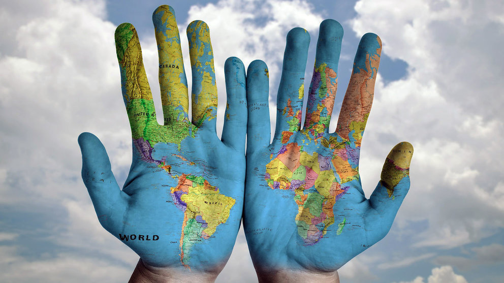 Una mapa del mundo reflejado sobre las manos de una persona