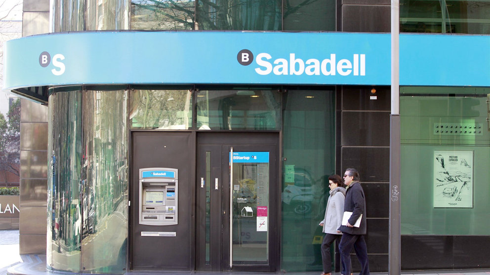 Dos personas pasan por delante de una oficina del Banco Sabadell.