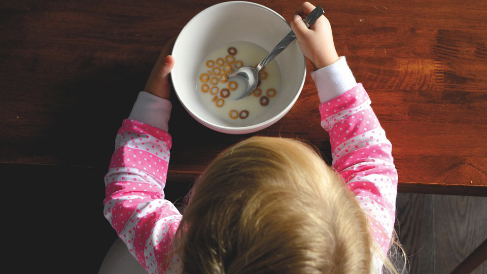 Una niña desayunando un cuenco de cereales alimentación salud comida niños