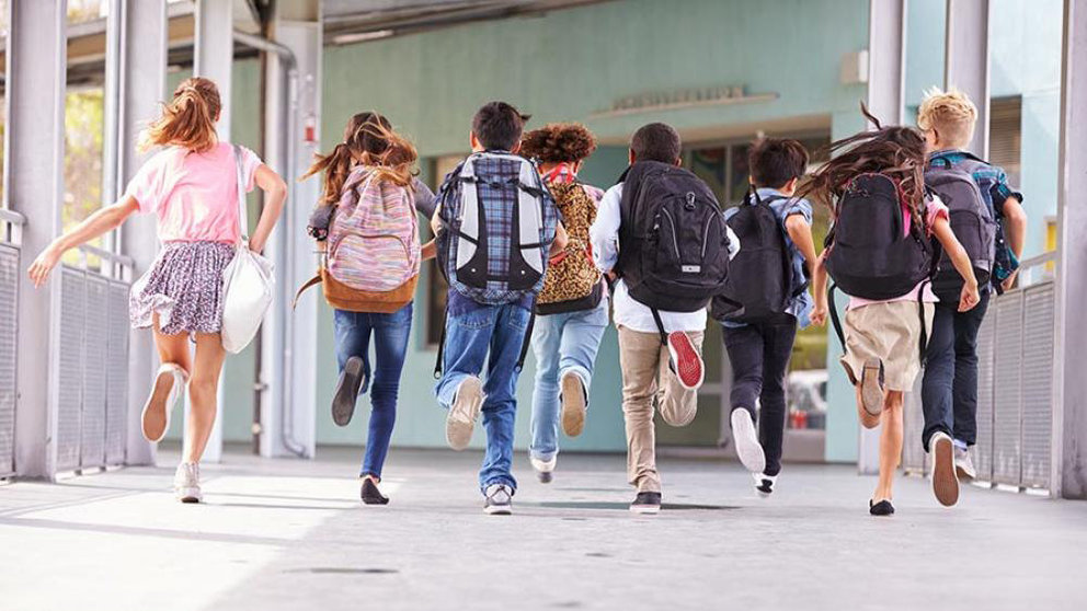 Varios niños salen corriendo con sus mochilas de un colegio. ARCHIVO
