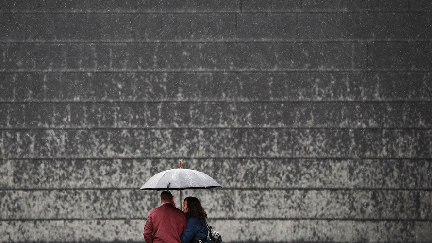 Una pareja se protege con un paraguas de la lluvia que desde primeras horas de la mañana cae sobre Pamplona. JESÚS DIGES EFE