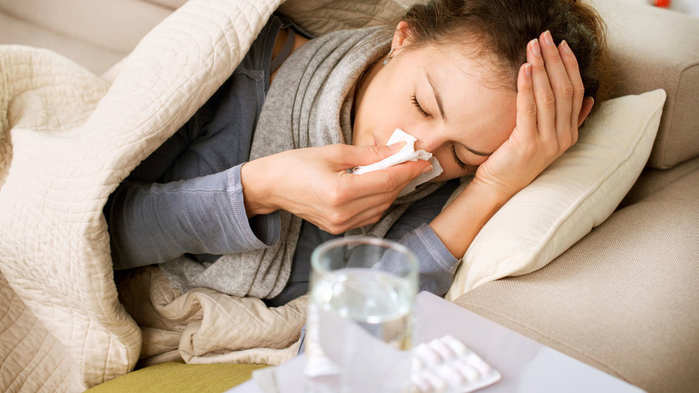 Una mujer se suena los mocos con un pañuelo tras tomar sus medicamentos para la gripe ARCHIVO