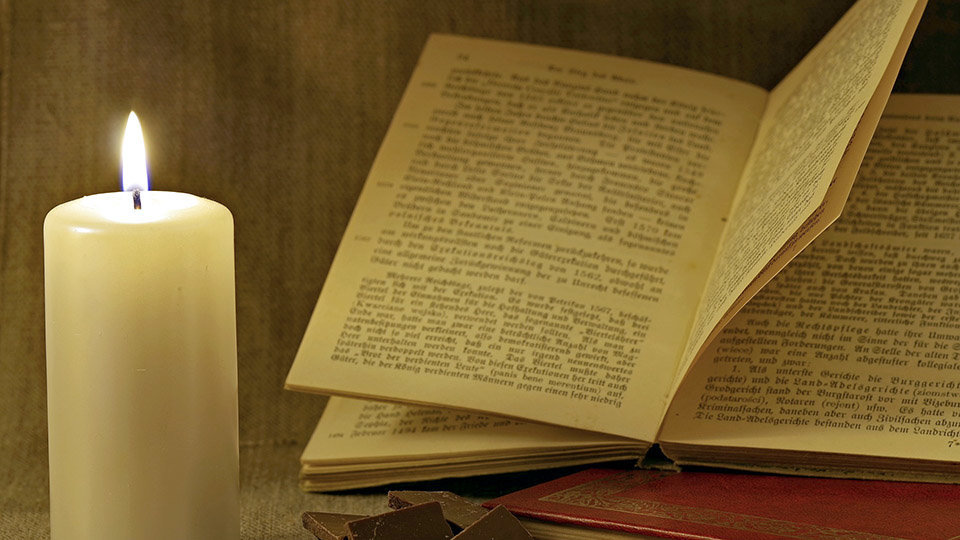 Lectura de un libro a la luz una vela