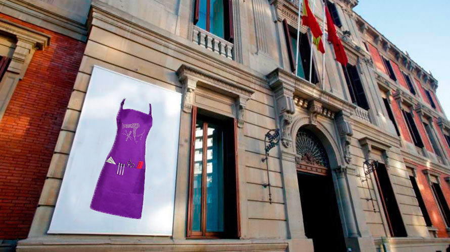 Fotomontaje de la fachada del Parlamento de Navarra con un cartel que contiene un delantal morado.
