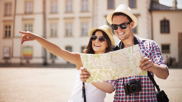 Imagen de una joven pareja haciendo turismo mientras revisan un mapa de los lugares que van a visitar ARCHIVO
