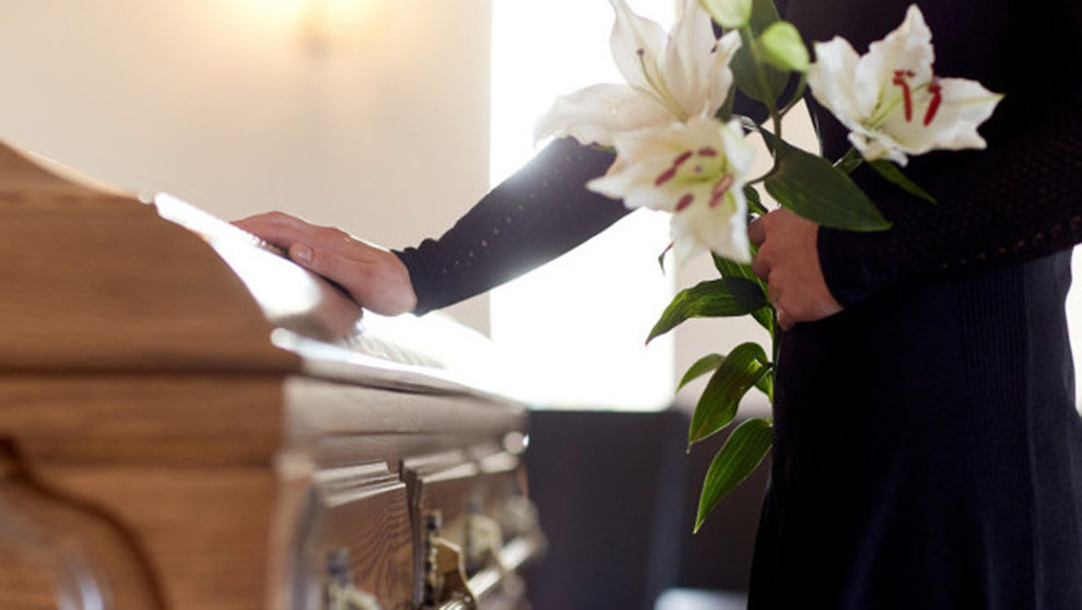 Imagen de una mujer en un funeral llorando frente a un ataud con un ramo de flores en memoria del fallecido ARCHIVO