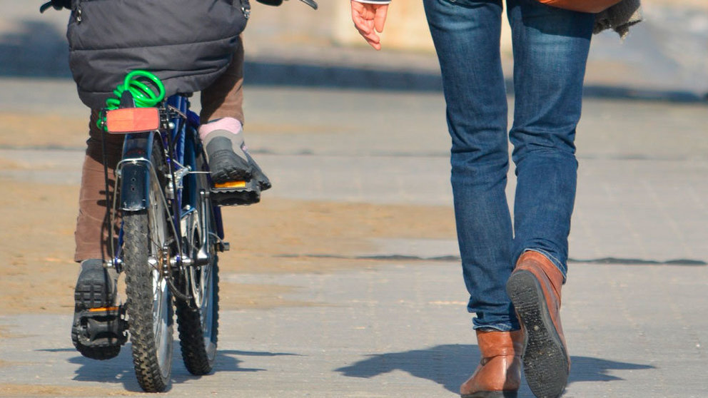 Un niño pasea con su bicicleta junto a su madre. ARCHIVO