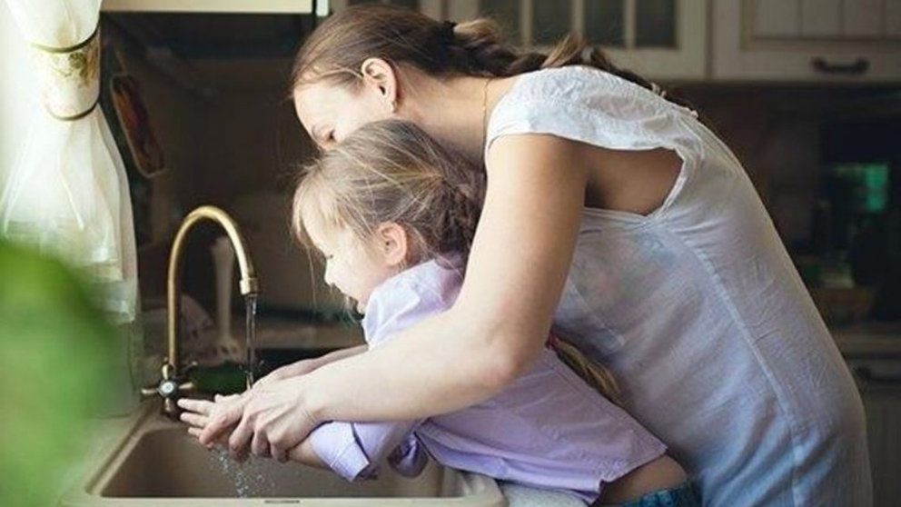Una niña se lava las manos con su madre en el grifo de agua de una cocina ARCHIVO