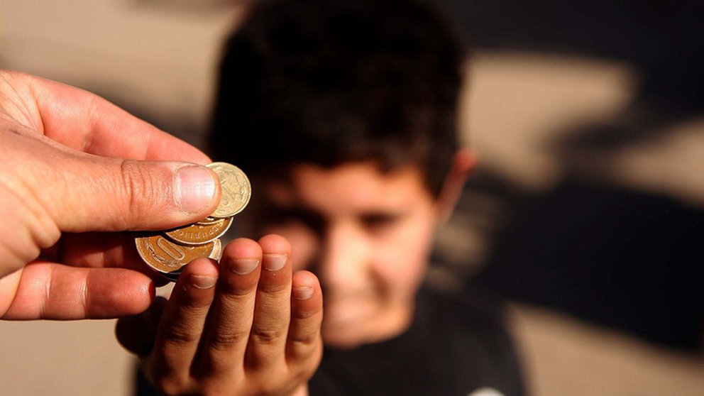 Imagen de archivo de un niño pidiendo limosna a una persona que le entrega varias monedas ARCHIVO