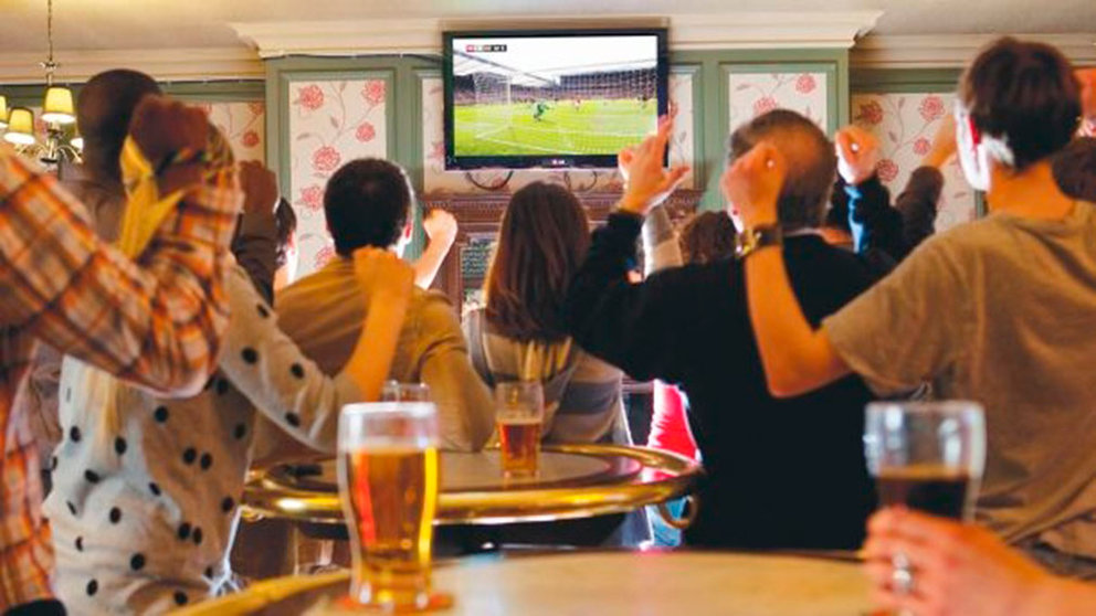 Varios clientes de un bar siguen la retransmisión de un partido de fútbol en la televisión ARCHIVO