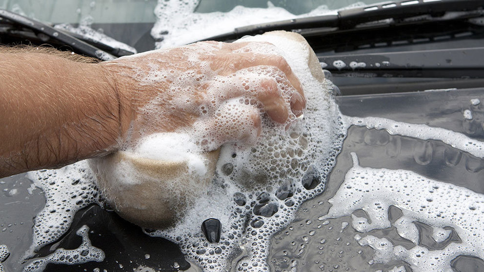 Una persona lava su coche en un túnel de lavado. 