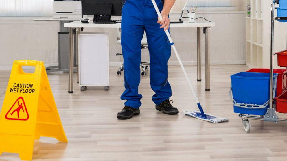 Imagen de un conserje trabajando en una oficina pasando la mopa para limpiar el suelo húmedo. ARCHIVO