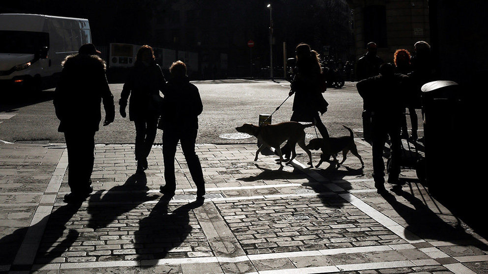 Un grupo de personas, algunas de ellas con sus perros atados con correas, pasean por el casco Viejo de Pamplona en un día marcado por el tiempo soleado a pesar de las frías temperaturas. EFE/Jesús Diges