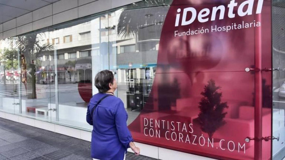 Una mujer se detiene ante uno de los carteles de una clínica iDental, la cadena low cost de dentistas que entró en quiebra ARCHIVO