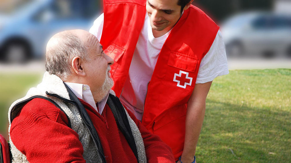 Imagen de un anciano con un asistente de Cruz Roja. CEDIDA