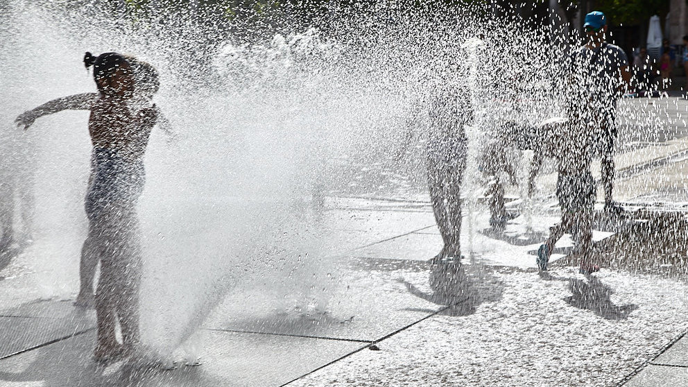 Unos niños juegan en la 'fuente de chorros' de la Plaza de Yamaguchi durante la primera ola de calor del verano en Pamplona. IÑIGO ALZUGARAY