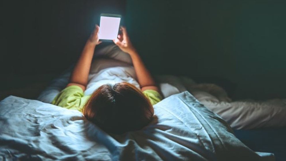 Una niña con su móvil en la cama ARCHIVO
