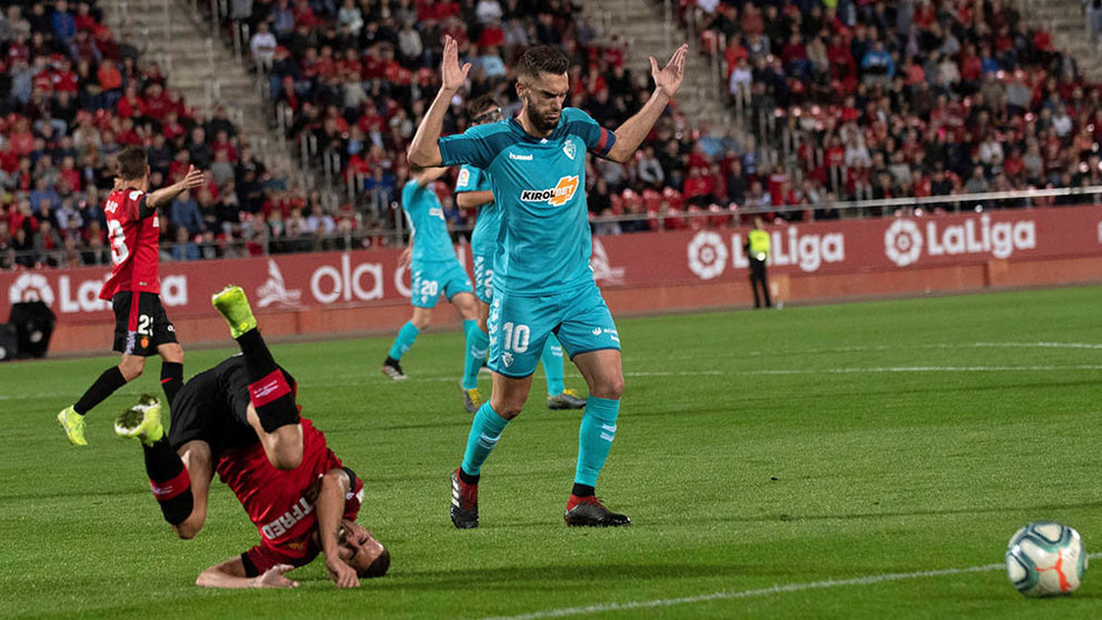 El centrocampista del RCD Dani Rodríguez (i) cae ante el centrocampista del Osasuna Roberto Torres (d), este jueves durante el partido de la undécima jornada de LaLiga que enfrenta al Mallorca y al Club Atlético Osasuna en el estadio Son Moix de Palma. EFE/ Cati Cladera