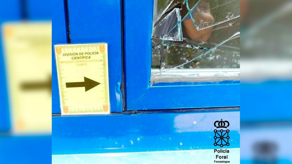 La ventana rota junto a un cartel de investigación de la Policía Foral. CEDIDA