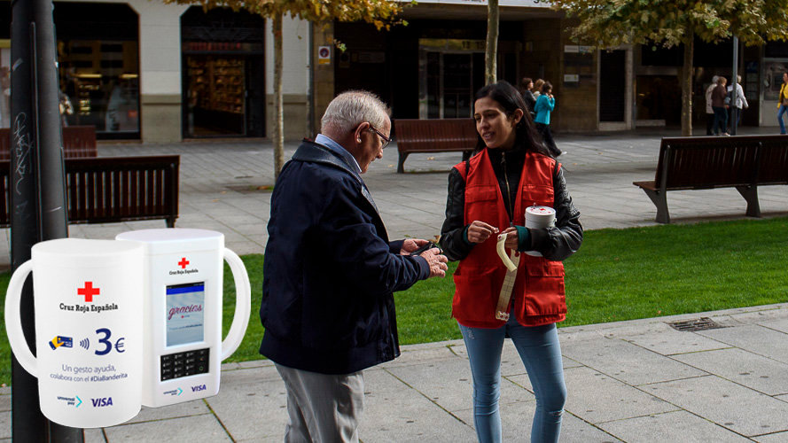 Una voluntaria recibe el donativo de un hombre en Pamplona durante el Día de la Banderita de Cruz Roja junto a una de las nuevas huchas contacless IÑIGO ALZUGARAY
