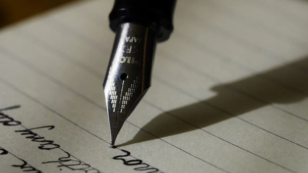 Una persona escribe con una pluma sobre un papel ARCHIVO