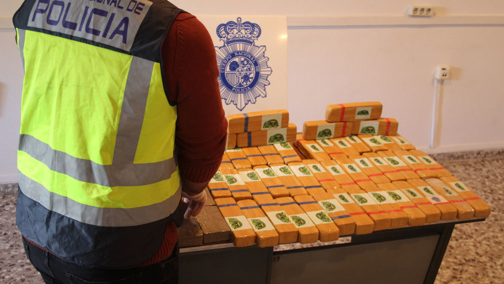 Un agente de la Policía Nacional inspecciona los paquetes de heroína incautados a dos personas en un vehículo de alta gama. CEDIDA