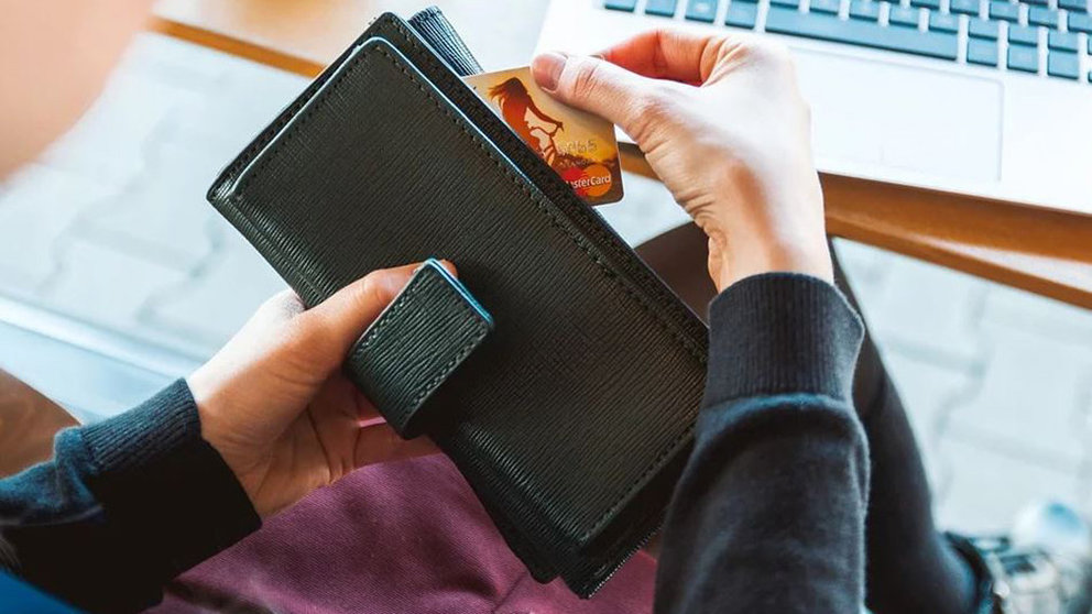 Una mujer saca su tarjeta de crédito para realizar un pago ARCHIVO