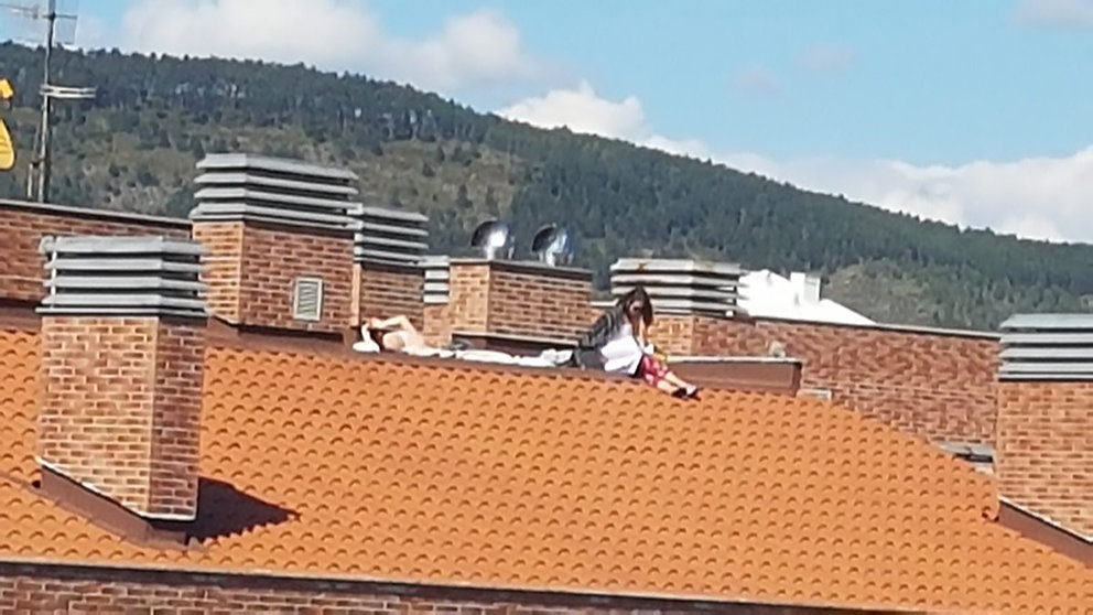 Dos jóvenes toman el sol encaramadas en el tejado desde una cuarta altura en Pamplona. POLICÍA MUNICIPAL