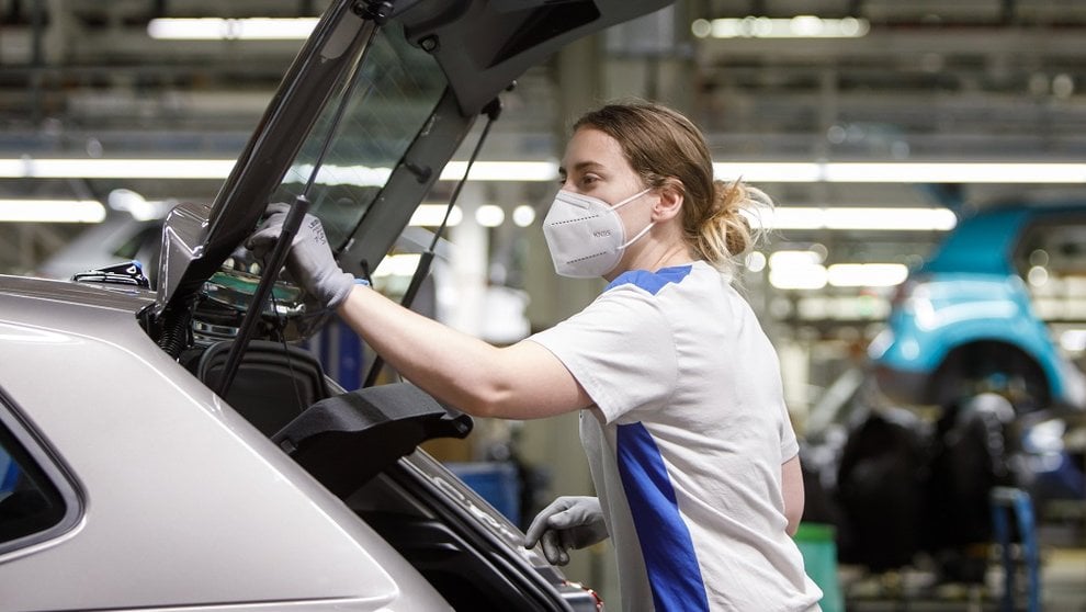 Una empleada de Volkswagen Navarra, con sus equipos de protección individual colocados, durante el desarrollo de su trabajo en el taller de Montaje. VW NAVARRA