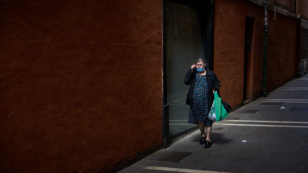Una mujer con mascarilla y la compra en la mano camina por las calles del casco viejo durante la crisis del coronavirus en Pamplona. Miguel Osés
