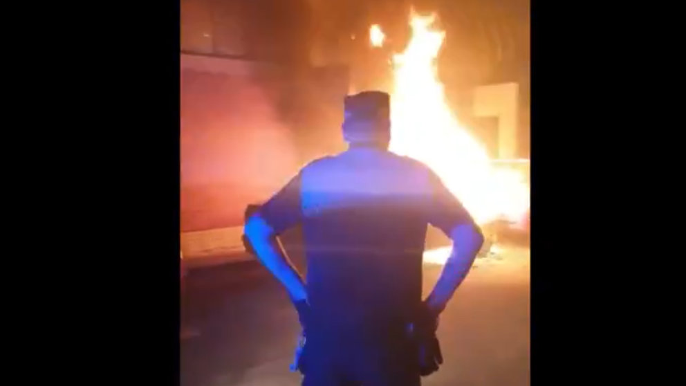 Un agente de la Policia Municipal vigila el incendio de un vehículo en Ermitagaña. TWITTER