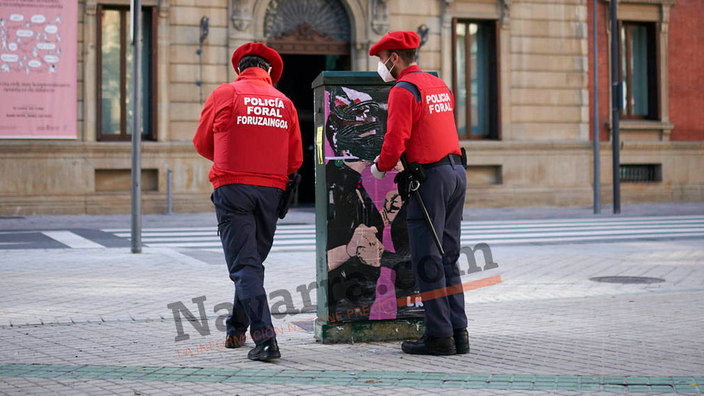 Dos agentes de la Policía Foral retiran el cartel del artista urbano LKN donde aparecían Bakartxo Ruiz y María Chvite besándose. PABLO LASAOSA