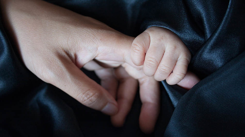 Un bebé le coge el dedo a su madre. ARCHIVO
