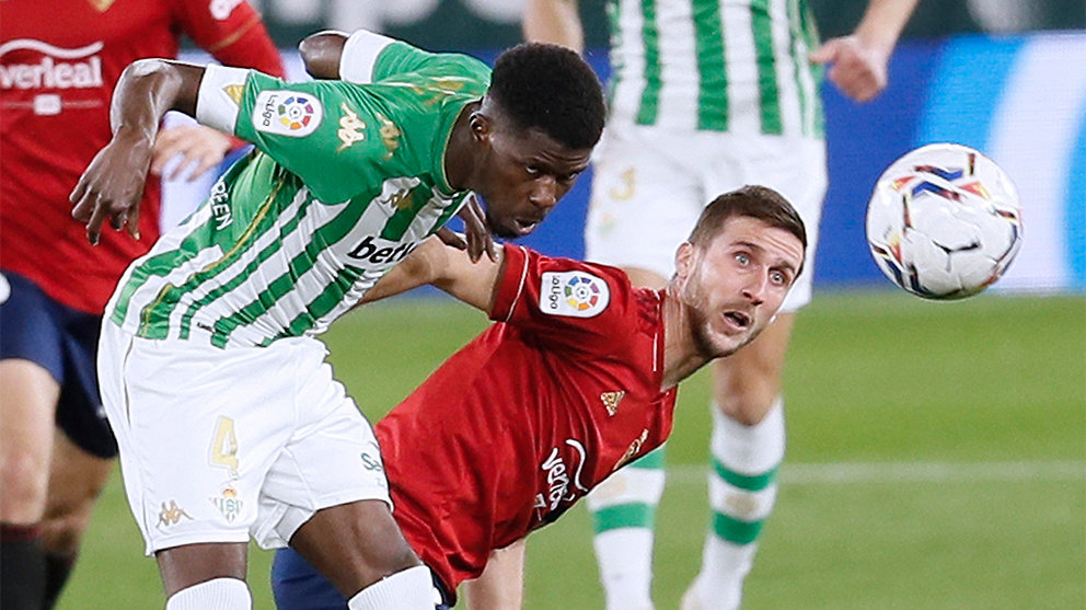 El centrocampista marfileño del Betis Paul Akouokou (i) pelea un balón con el centrocampista de Osasuna Oier Sanjurjo durante el partido de LaLiga disputado esta noche en el estadio Benito Villamarín. EFE/Jose Manuel Vidal.