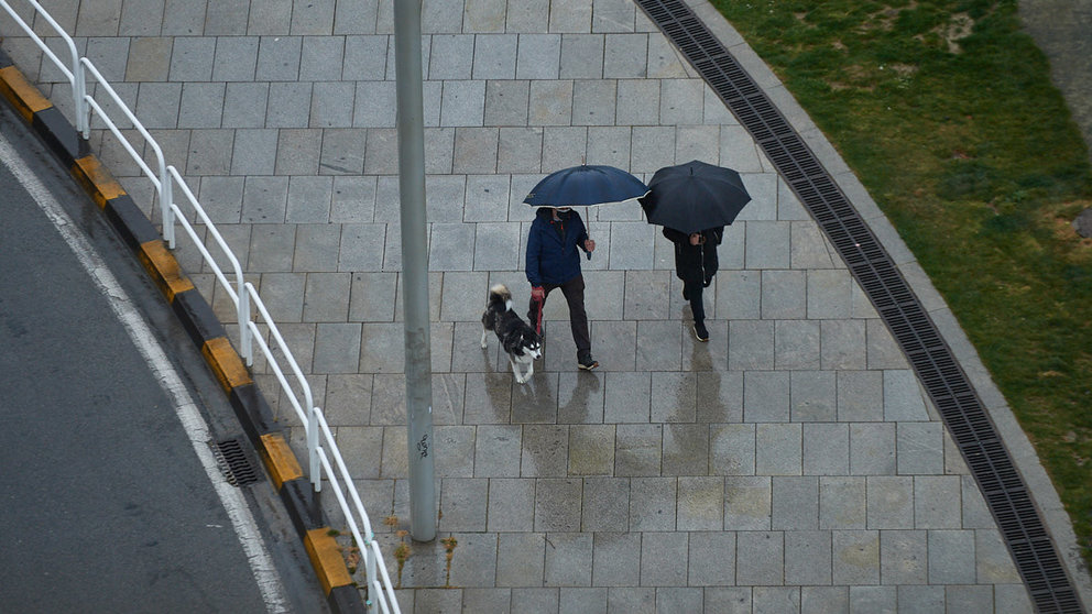 Dos personas con paraguas caminan bajo la lluvia por las calles de Pamplona durante la crisis de la pandemia del coronavirus. MIGUEL OSÉS