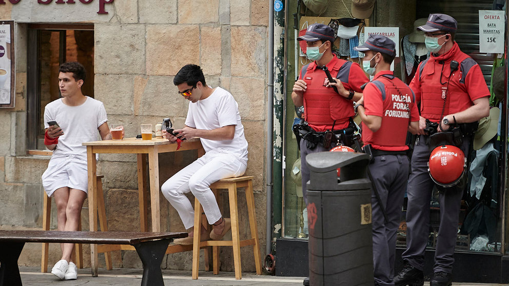 Varios jóvenes toman cervezas junto a policías forales en las no fiestas de San Fermín de 2021. PABLO LASAOSA