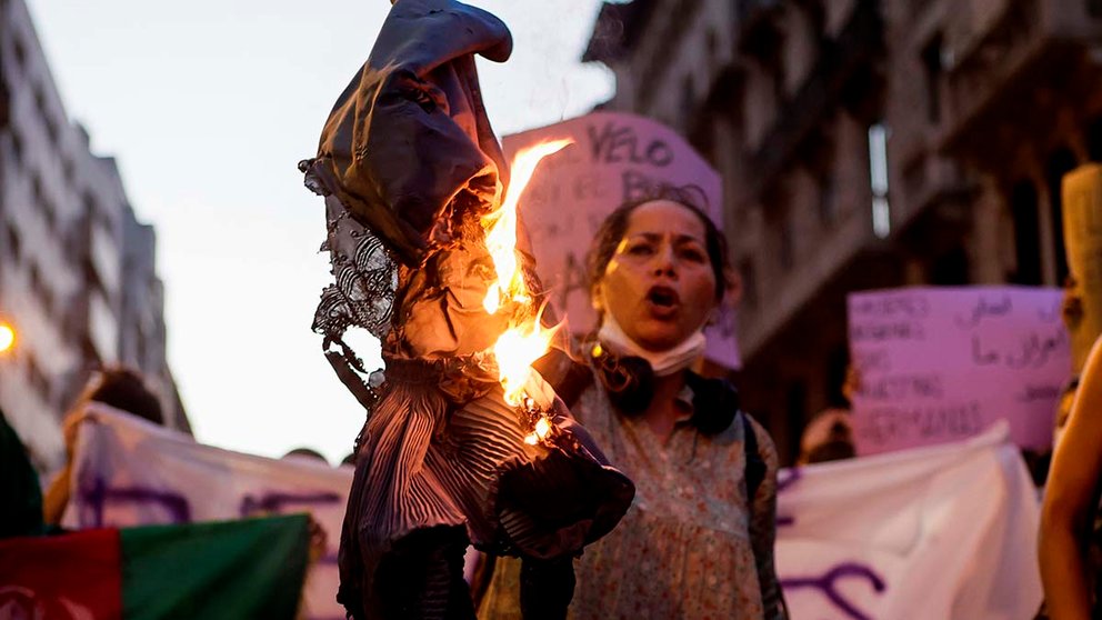 Mujeres afganas residentes en Barcelona acompañadas por la agrupación Catalunya Abolicionista Plataforma Feminista (CATAB) queman un burka durante las protestas ante la sede de la ONU en la Barcelona en las que reclaman una respuesta internacional urgente para proteger a las mujeres y niñas afganas tras la victoria de los talibanes. EFE/Quique Garcia