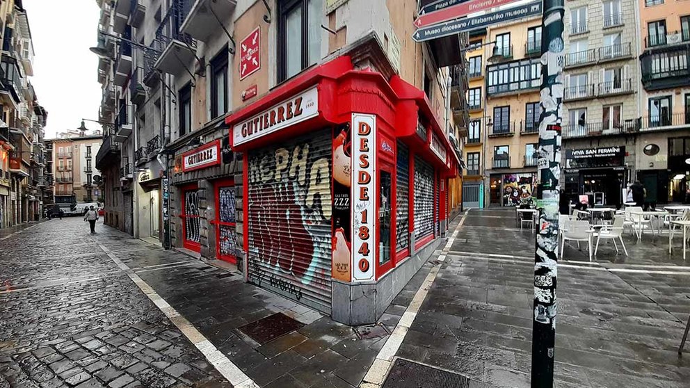 Un poste turístico y un persiana de un negocio cubierta de pegatinas y pinturas. PSN DE PAMPLONA
