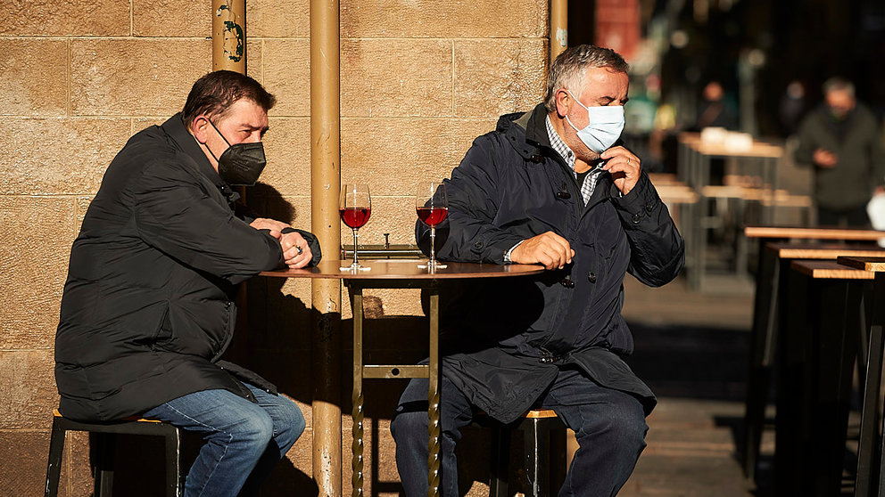 Dos hombres con mascarilla toman un vino en un bar de la calle Estafeta de Pamplona. PABLO LASAOSA