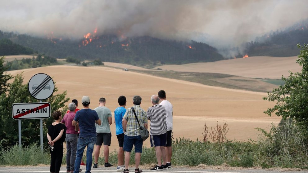 Varias personas miran este sábado un incendio desde las afueras de la localidad de Astráin (Pamplona). EFE / Villar López