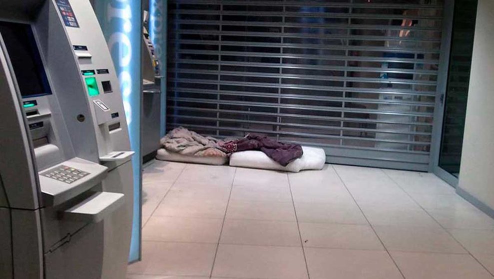 Una persona sin hogar con sus pertenencias en un cajero de un banco. ARCHIVO