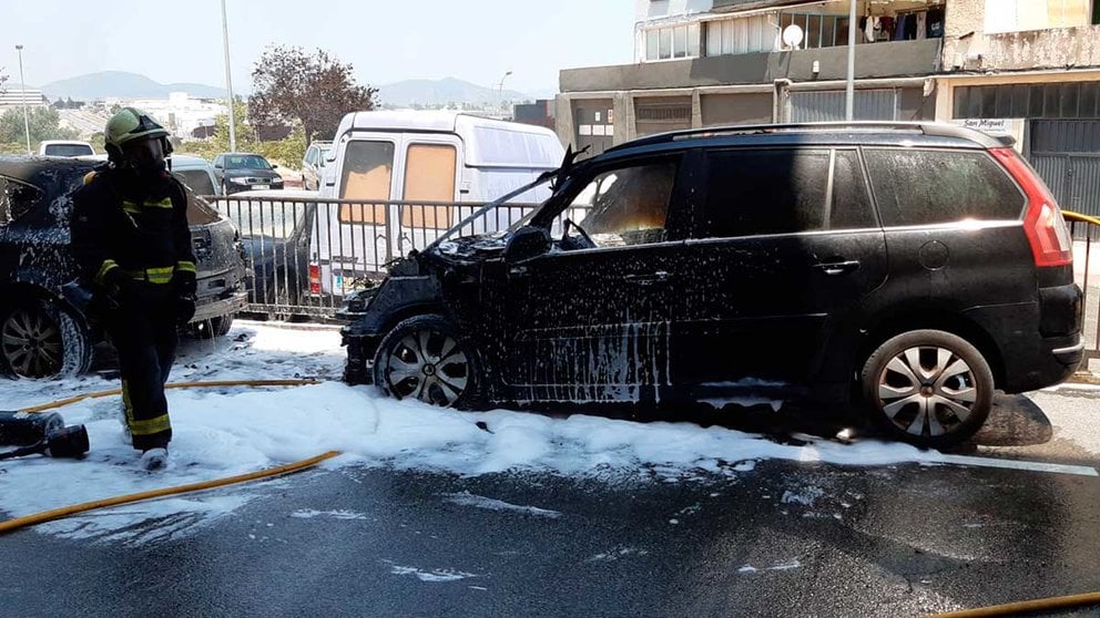 Un bombero del parque de Cordovilla termina de apagar el vehículo quemado en Noain. BOMBEROS DE NAVARRA